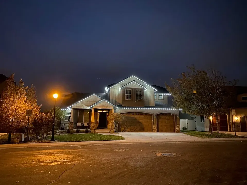 Two-story craftsman home with cool white C9 lights on every roofline peak