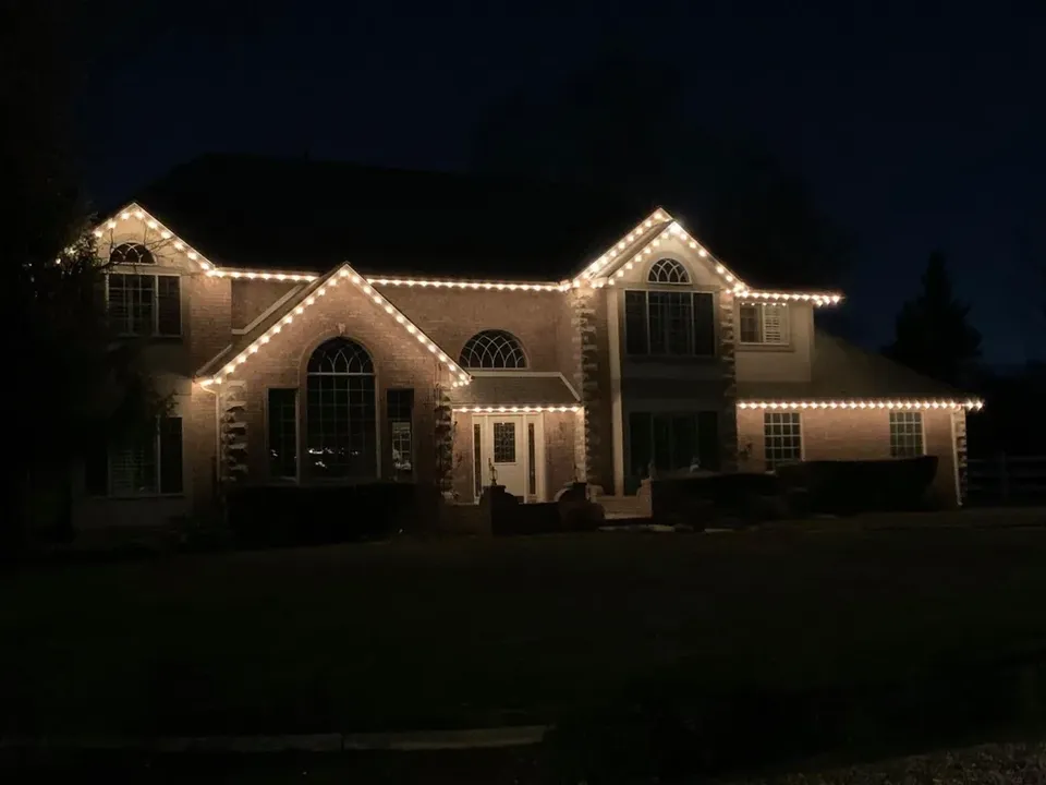 Large brick two-story home with warm white lights on all gables